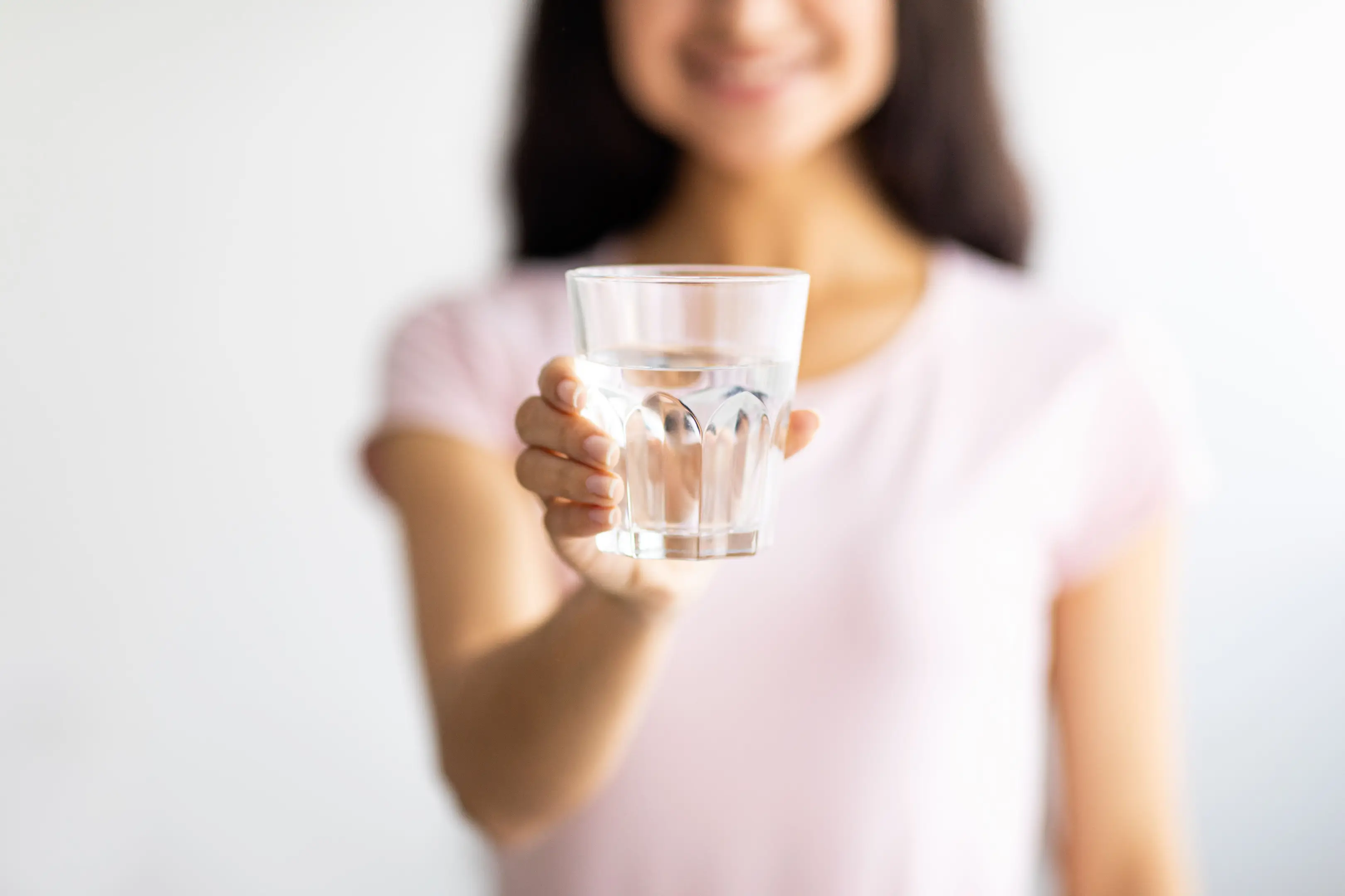 コップの水を見せながら微笑む女性