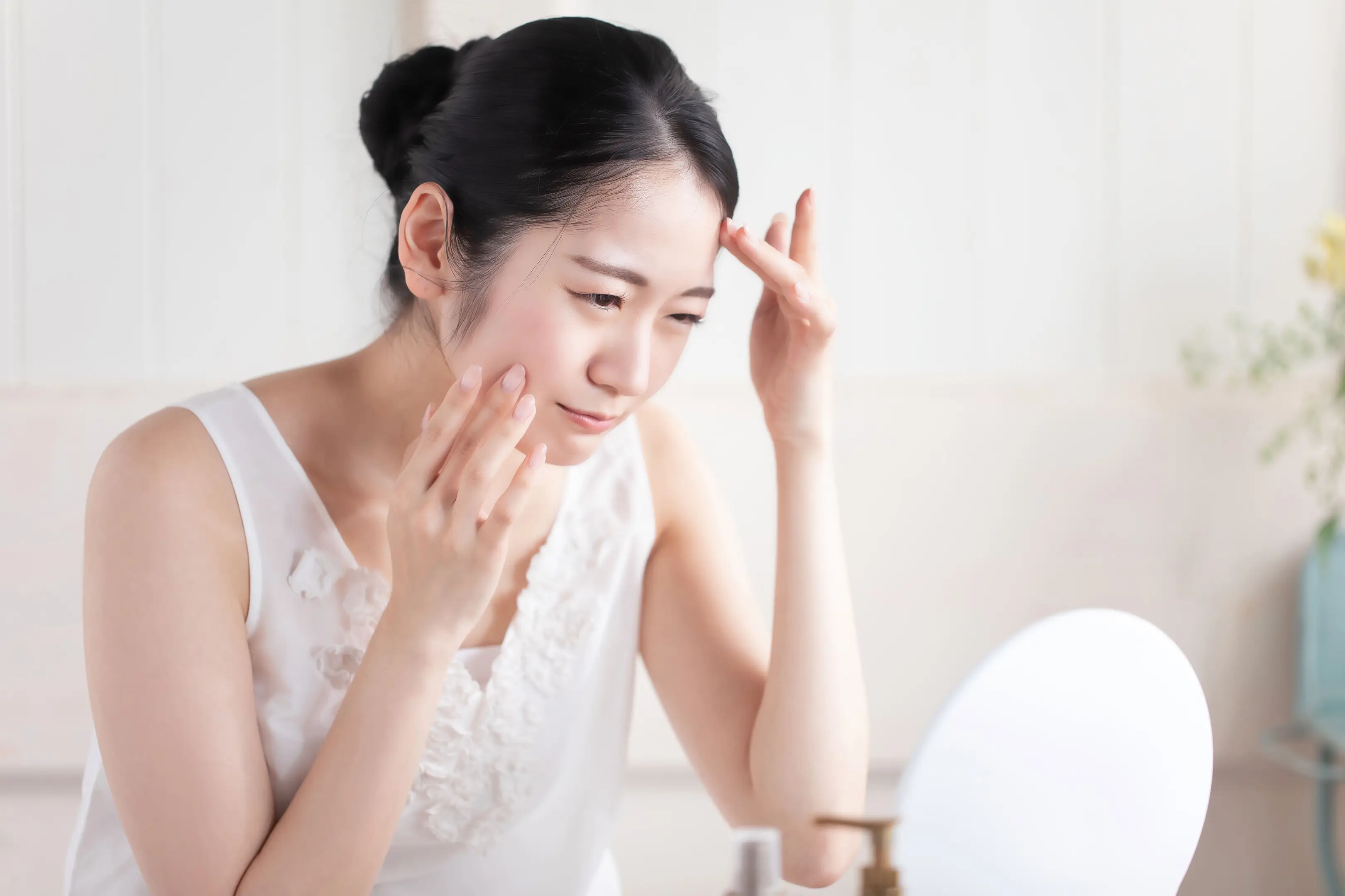 鏡を見ながら肌悩みを気にしている女性