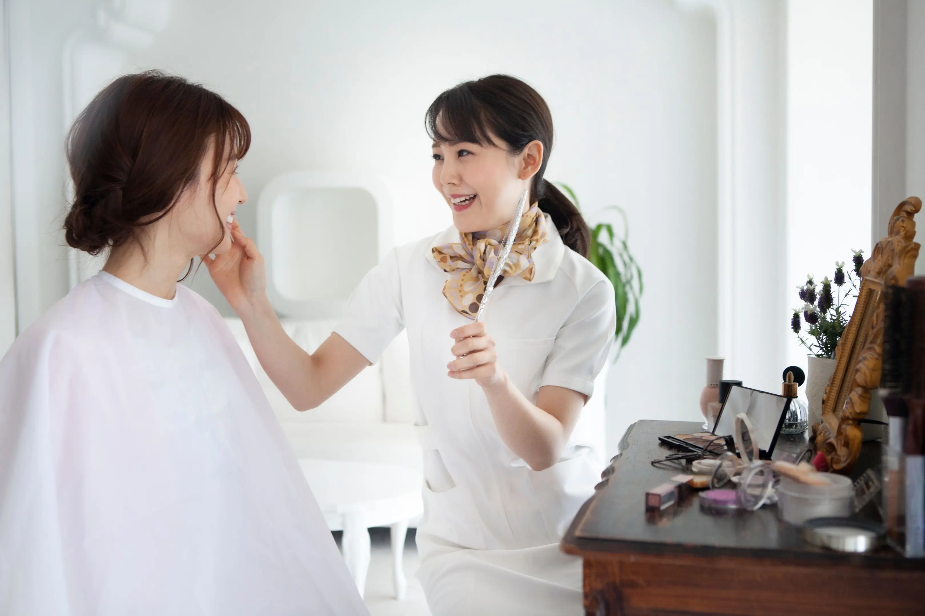 化粧品カウンターでタッチアップを受ける女性と美容部員